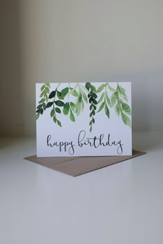 a white card with green leaves and the words happy birthday