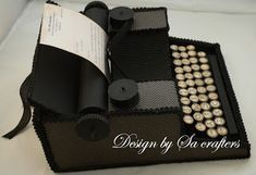 an old fashioned typewriter is decorated with black and gold buttons, ribbon, and paper