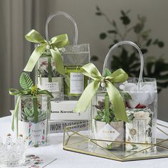 several small gift bags with green bows on them sitting on a table next to a glass vase