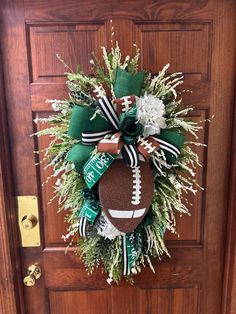 a football wreath on the front door with green and white ribbons hanging from it's side