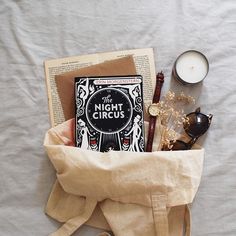 an open book and some other items in a bag on top of a white sheet