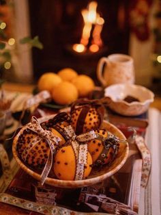 some oranges are in a bowl on a table next to a christmas tree and candles