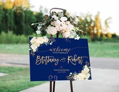 a blue sign with white flowers on it that says welcome to the bride and groom