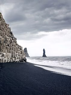 the black sand beach is lined with large rocks