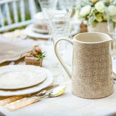 the table is set with plates, silverware and vases on top of it