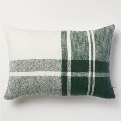 a green and white plaid pillow sitting on top of a white table next to a wall