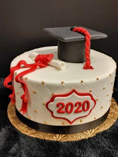 a graduation cake is decorated with red ribbon and a mortar cap on top that reads 2020