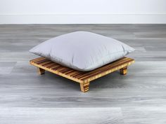 a pillow sitting on top of a wooden platform in the middle of an empty room