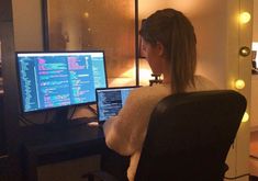 a woman sitting in front of a computer monitor