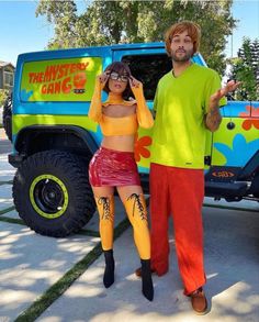 a man and woman dressed up in costumes standing next to a truck with the words mystery gang on it