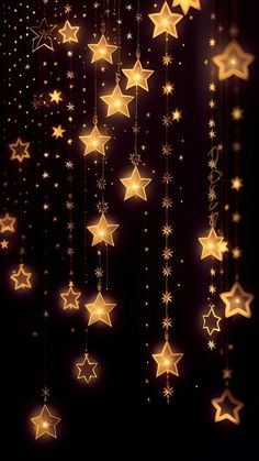 some gold stars hanging from strings on a black background with lights in the shape of stars