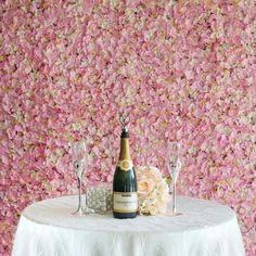 a table topped with a bottle of champagne next to two wine glasses and a bouquet of flowers