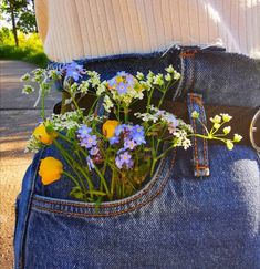 a person is holding flowers in their back pocket, with the jeans pockets rolled down