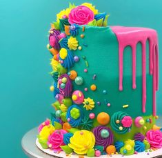 a multicolored cake with icing and flowers on it