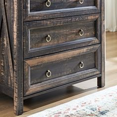 a wooden dresser with three drawers on top of it and a rug in the background