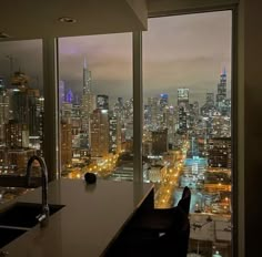 a kitchen with a view of the city lights and skyscrapers from it's windows