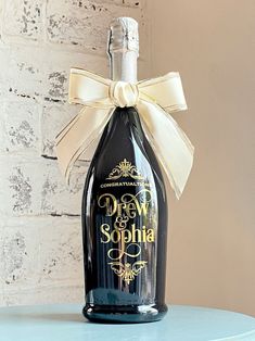 a bottle of wine with a bow on it sitting on top of a blue table