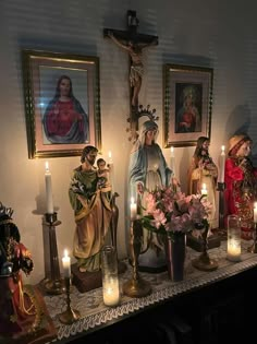 a table topped with statues and candles next to paintings