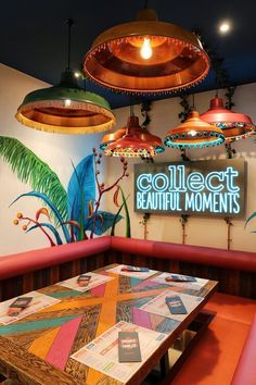 the interior of a restaurant with colorful lights and artwork on the walls, along with wooden benches