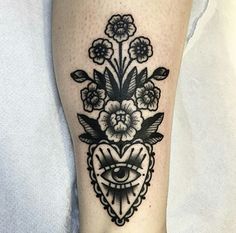 a black and white tattoo on the leg of a woman's foot with an all seeing eye surrounded by flowers