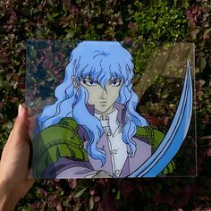 a person holding up a card with an anime character on it in front of some bushes