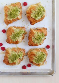 four croissants with pesto on top and raspberries around them