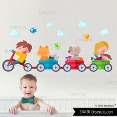 a baby sitting in a crib next to a wall with animals and cars on it