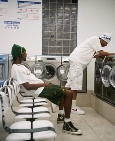 two men are sitting in front of washers and looking at each other's clothes