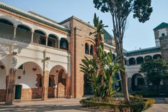 an old building with many arches and trees in front of it on a sunny day