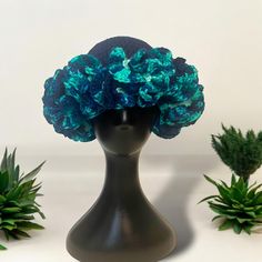 a black mannequin head with blue flowers on it and succulents in the background