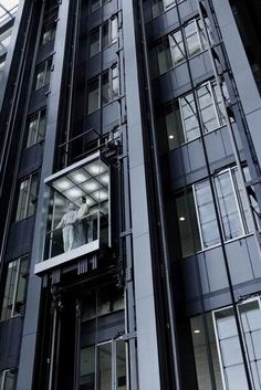 a tall building with glass windows and a statue on the window sill in front of it