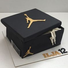 a black box with gold jordan logo on the top and bottom is sitting on a white table