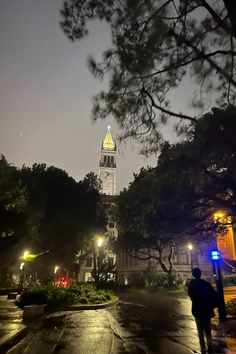 a tall clock tower towering over a city at night with street lights on it's sides