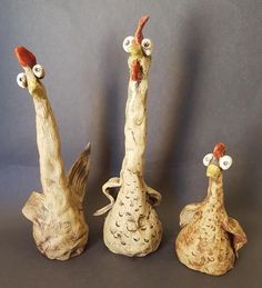 three ceramic chickens are standing next to each other on a gray background, one is looking at the camera