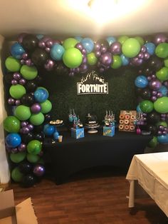 a table topped with lots of balloons next to a wall