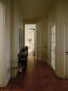 an empty hallway with wooden floors and white walls