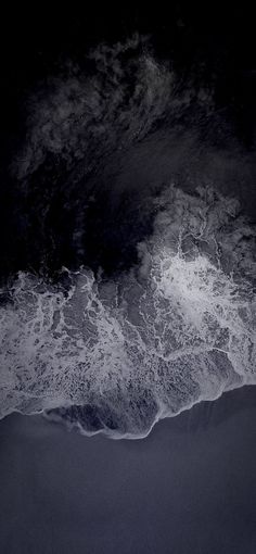 an aerial view of the ocean with waves coming in to shore and dark sky above