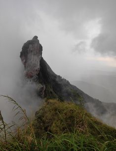 the mountain is covered in fog and mist as it sits on top of a hill