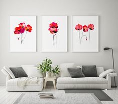 three paintings on the wall above a couch in a living room with white walls and flooring