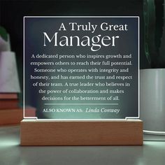 a plaque that reads a truly great manager on the table next to a potted plant