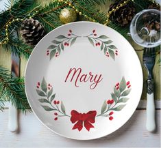 a white plate with a red bow on it next to pine cones and evergreen branches