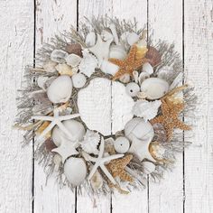 a wreath made out of seashells and starfish on a white wooden background