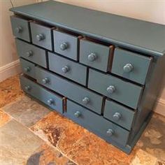 a blue dresser sitting on top of a tile floor next to a wall and door