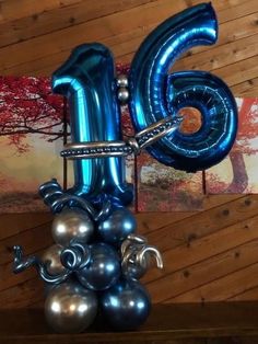 a blue balloon shaped like the number five with silver balls on it's bottom