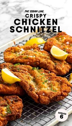 the crispy chicken schnitzel is served on a cooling rack with lemon wedges