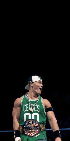 a man in a green shirt and hat standing next to a wrestling ring