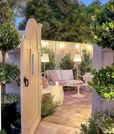 an outdoor living area is lit up with lights and greenery on either side of the door