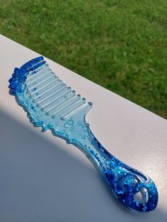 a blue toothbrush sitting on top of a white table next to green grass in the background