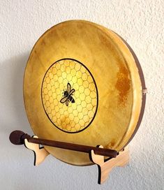 a wooden plate with a bee on it hanging from a hook in a wall next to a white wall