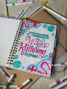 a notebook with writing on it surrounded by markers and crayons